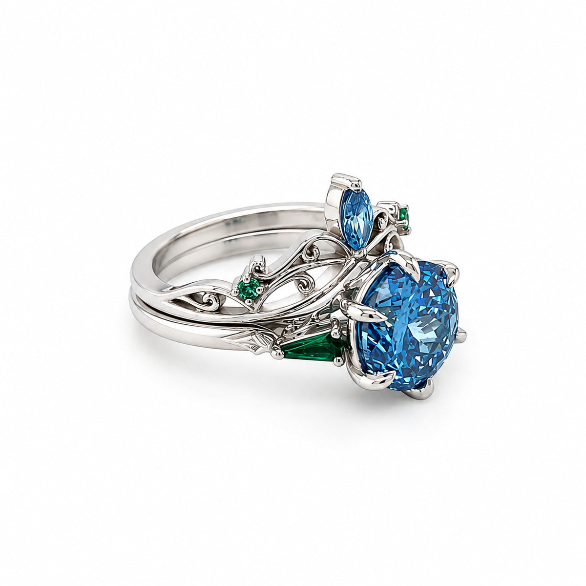 Coordinating platinum engagement ring and tiara-inspired wedding band with blue diamonds and green emeralds