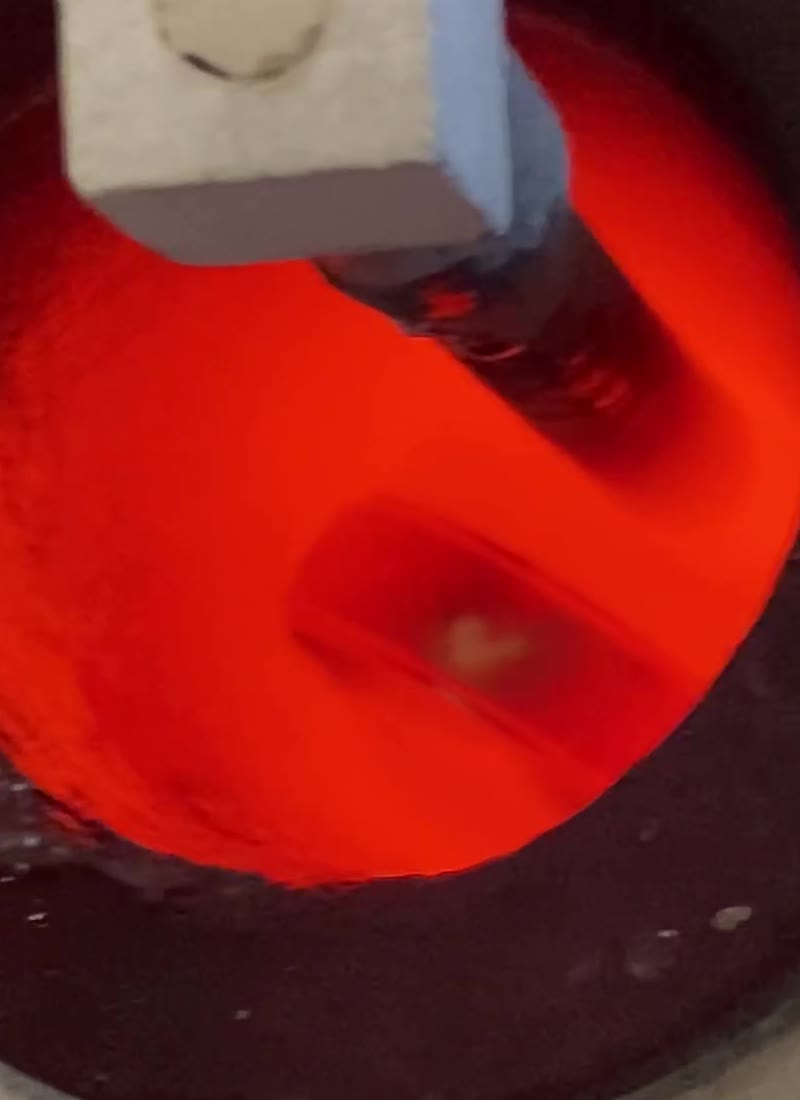 A frame from the original melting footage showing the small heart-shaped form in the heated gold