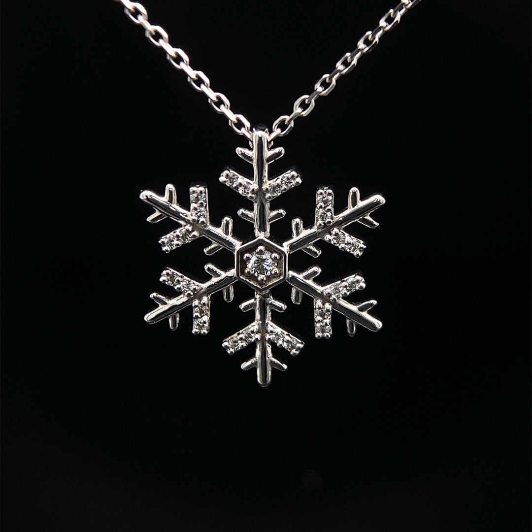 A 14 karat white gold snowflake diamond necklace with adjustable chain.