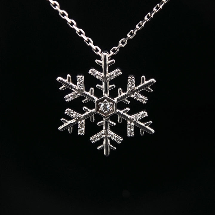 A 14 karat white gold snowflake diamond necklace with adjustable chain.