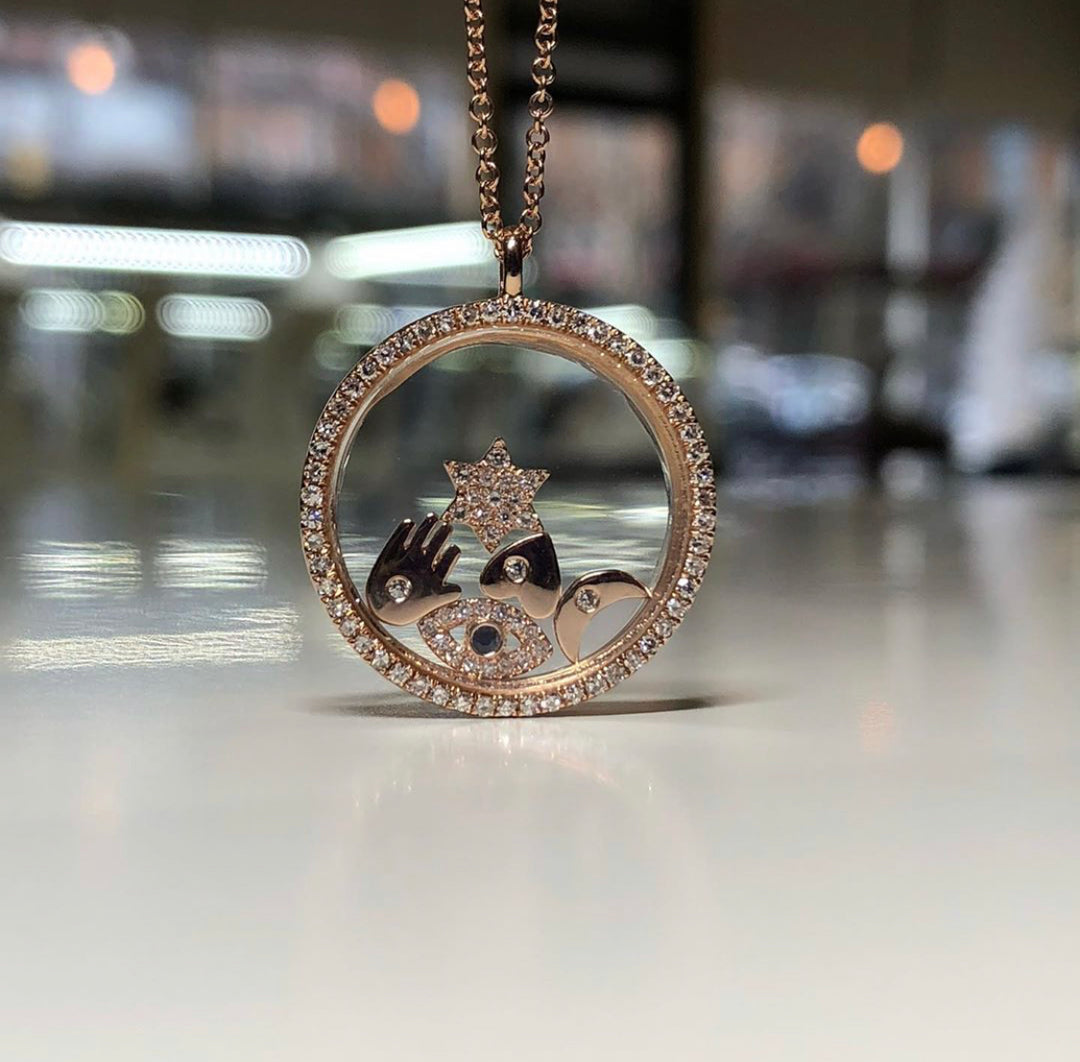 A 14KT rose gold diamond floating charm pendant necklace with a cable chain and multiple charms including a crown and heart, displayed on a mannequin.
